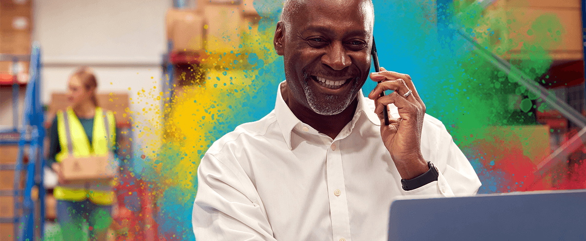 Man in a warehouse smiling whild talking on the phone